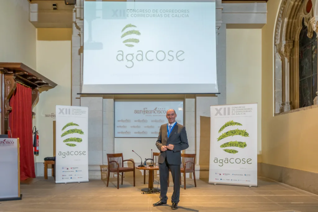 El director de Galicia Business School posando en el escenario del XII Congreso de Corredores y Corredurías de Galicia (Agacose), celebrado en el Hotel San Francisco en Santiago de Compostela, documentado por Whitebox Portraits.