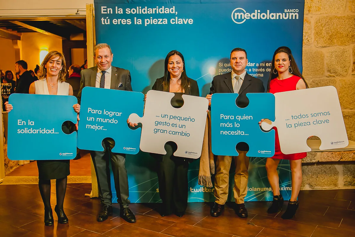 Fotografía para eventos solidarios en Galicia: Cinco personas sosteniendo piezas de un puzzle con frases solidarias en el photocall del Banco Mediolanum.