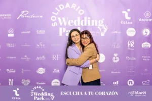 Rosa Echevarría, presidenta del Wedding Pack Solidario, y Nuria de ArtesaNuRa, en un cálido abrazo sonriente frente al photocall del evento.