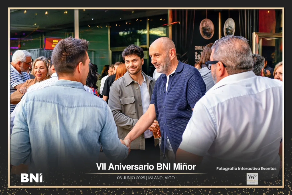 Foto de asistentes saludándose durante la bienvenida en el evento empresarial.
