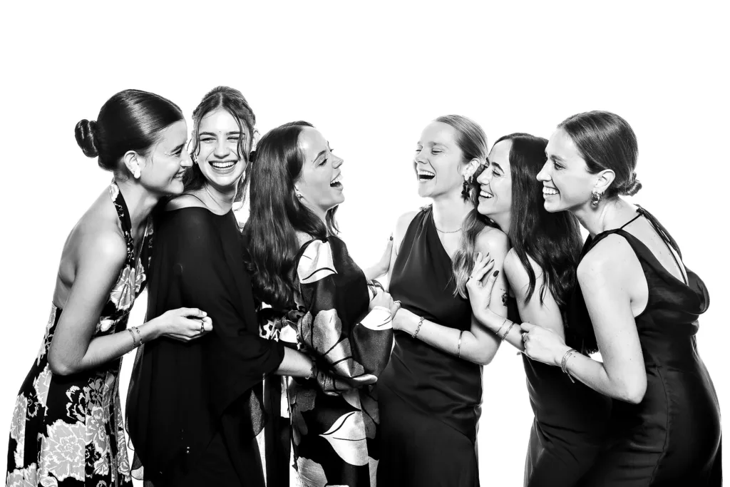 Grupo de invitadas sonriendo en un set de fotografía profesional con fondo blanco en una boda en Galicia.